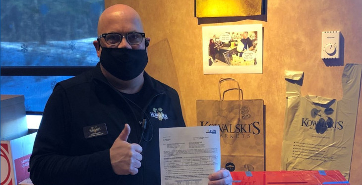 grocery worker giving thumbs up with union contract