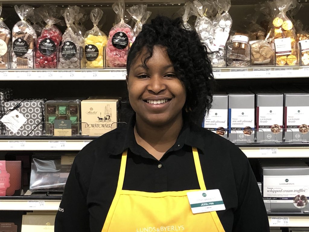 grocery worker standing in front of chocolate shelf